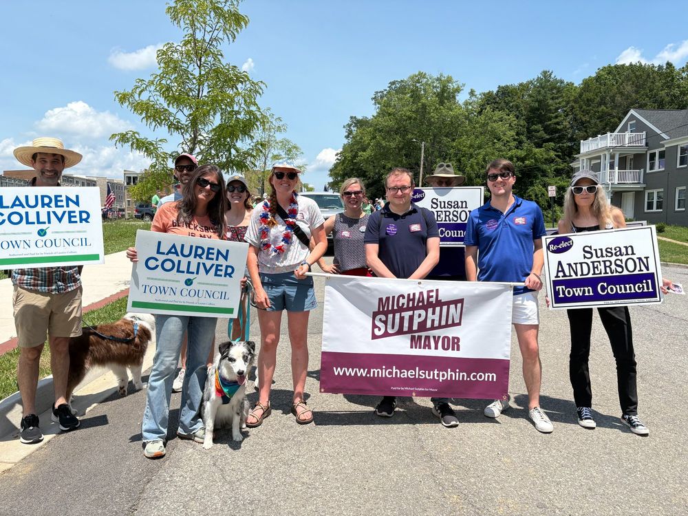 A group in the Backsburg parade holding signs for Michael Sutphin, Lauren Colliver, and Susan Anderson