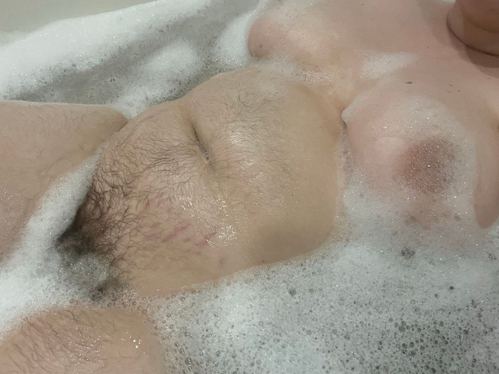 a picture of ty in the bath. his body is surrounded by small bubbles with all of his hairy tummy exposed. there are some bubbles between his thighs and on his tits.