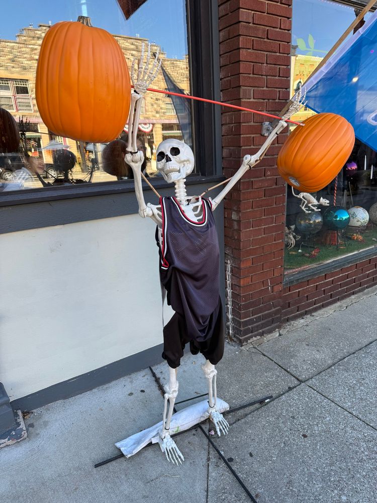 Decoration of a skeleton lifting a barbell with pumpkins as weights