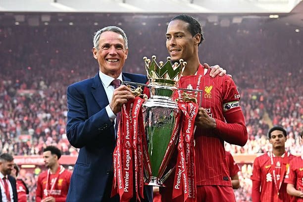 Virgil Van Dijk and Alan Hansen hold the Premier League trophy in front of the Kop at Anfield.