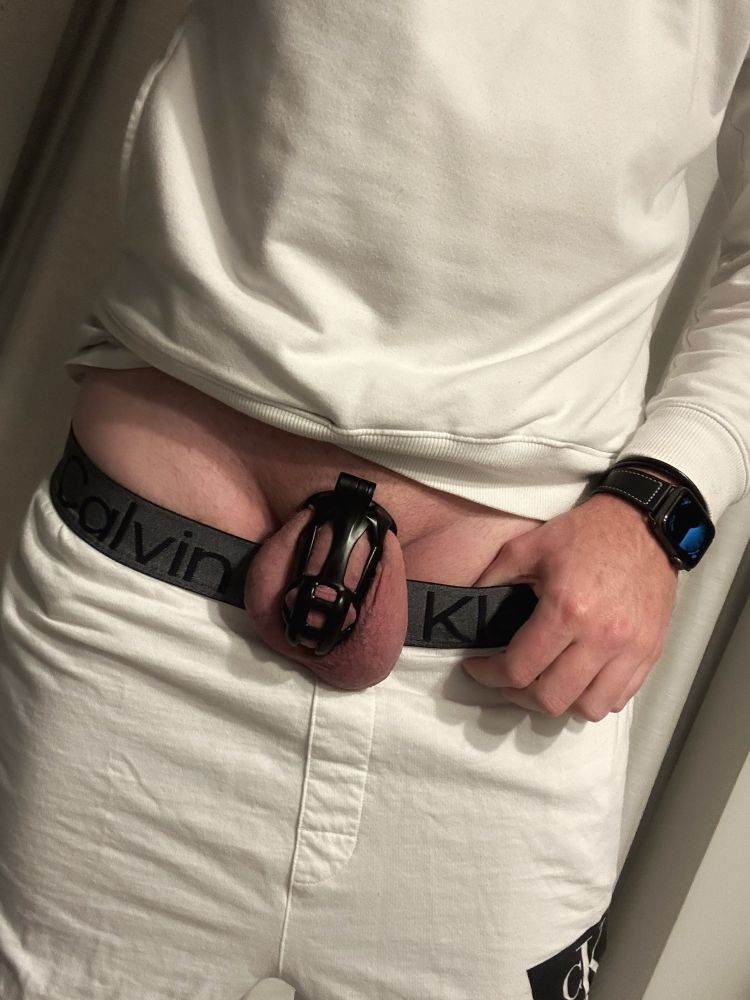 Me wearing a white hoodie and white sweatpants slightly pulled down to show a chastity cage