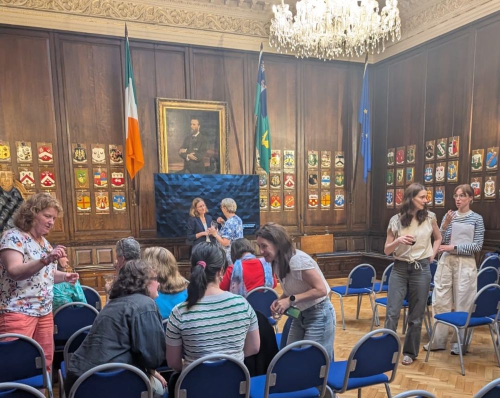 A crowd of people talking in a wood panelled room