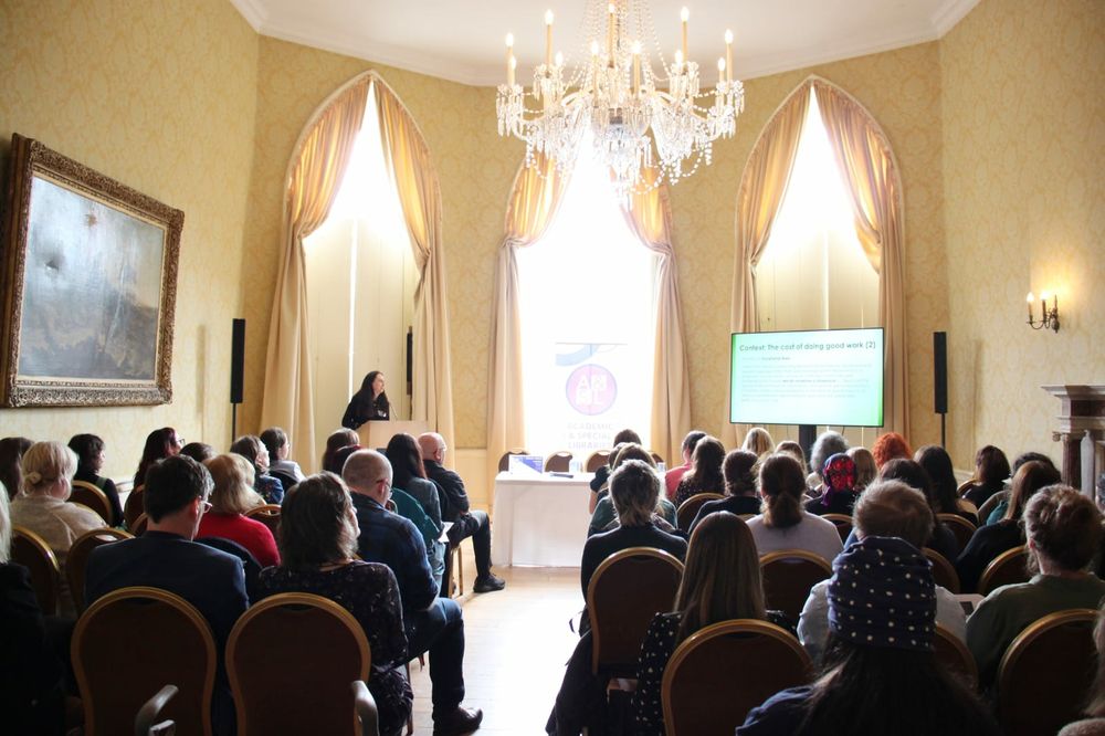 A woman speaks from a lectern to a seated audience