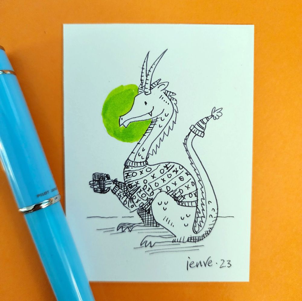 A pen and ink drawing of a happy dragon wearing a sweater and holding a mug of something warm. The tip of their tail is being warmed by a knitted hat with a pompom.