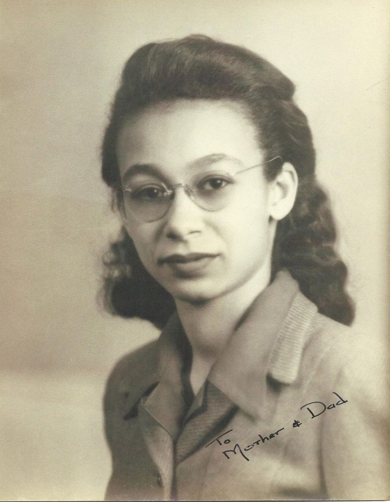 Black & white portrait of a woman in suit jacket and glasses. She has signed the photo “To Mother & Dad”