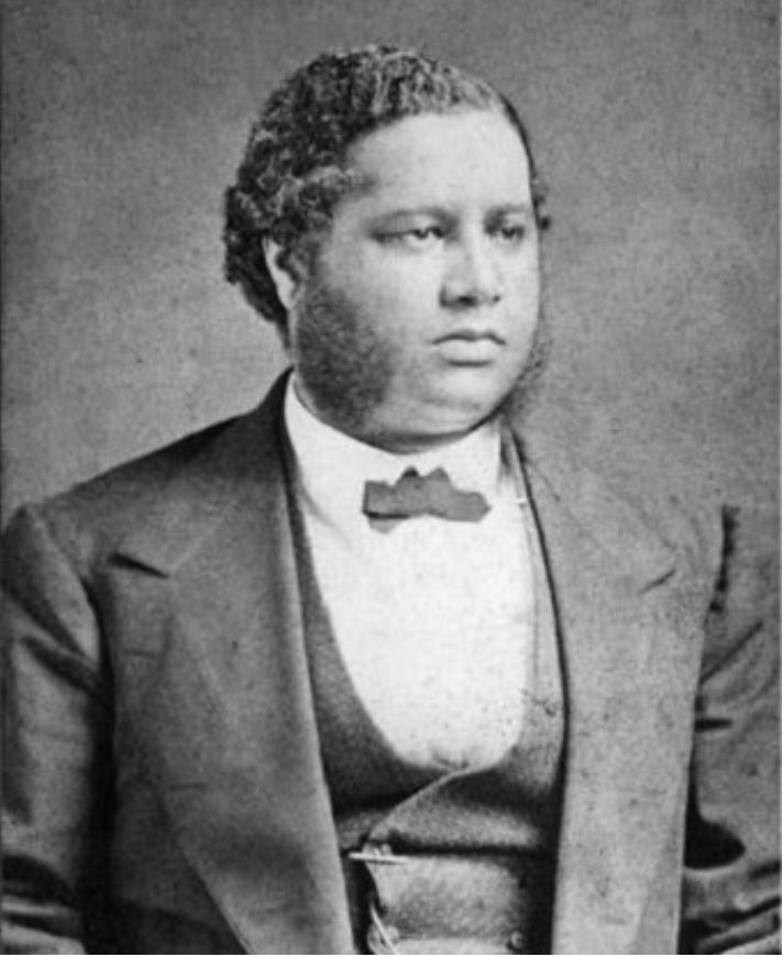 Black and white photo of a man in coat, vest, and tie with mutton chop sideburns. 