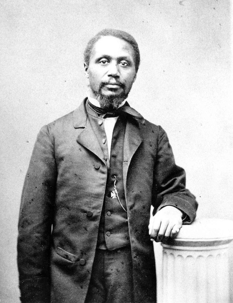 Formal portrait of man in suit coat, waistcoat, and tie with a watch chain. He is gazing directly at the viewer.