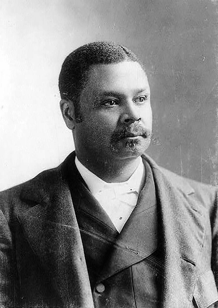 Portrait of a man coat, vest, and white tie gazing to toward the light.