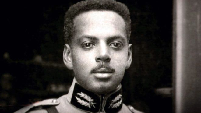 Black and white photo of a young man with a mustache. 