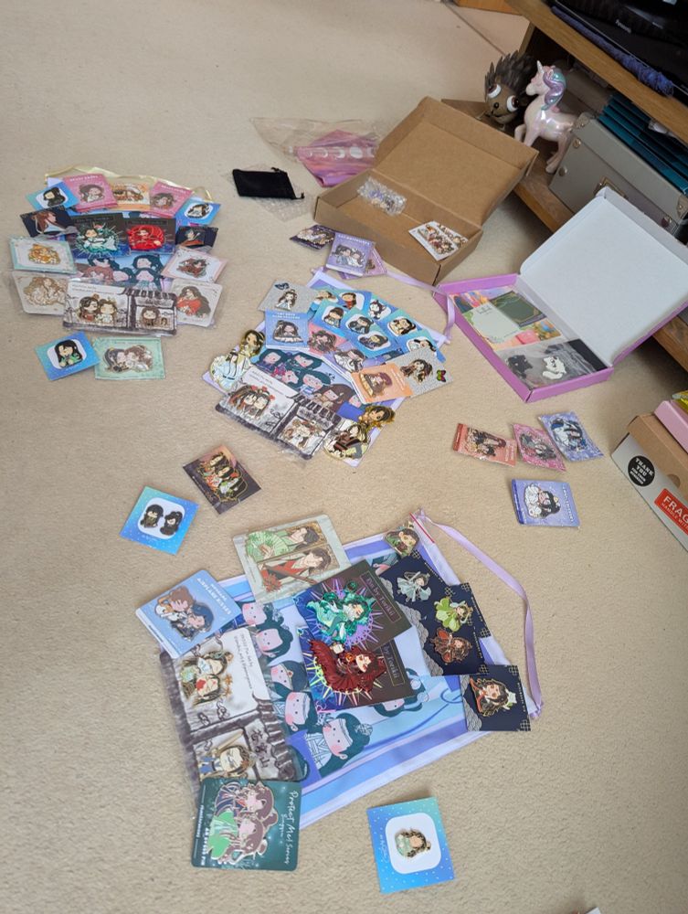Pin badges and banners spread on the carpet, roughly positioned for putting together 