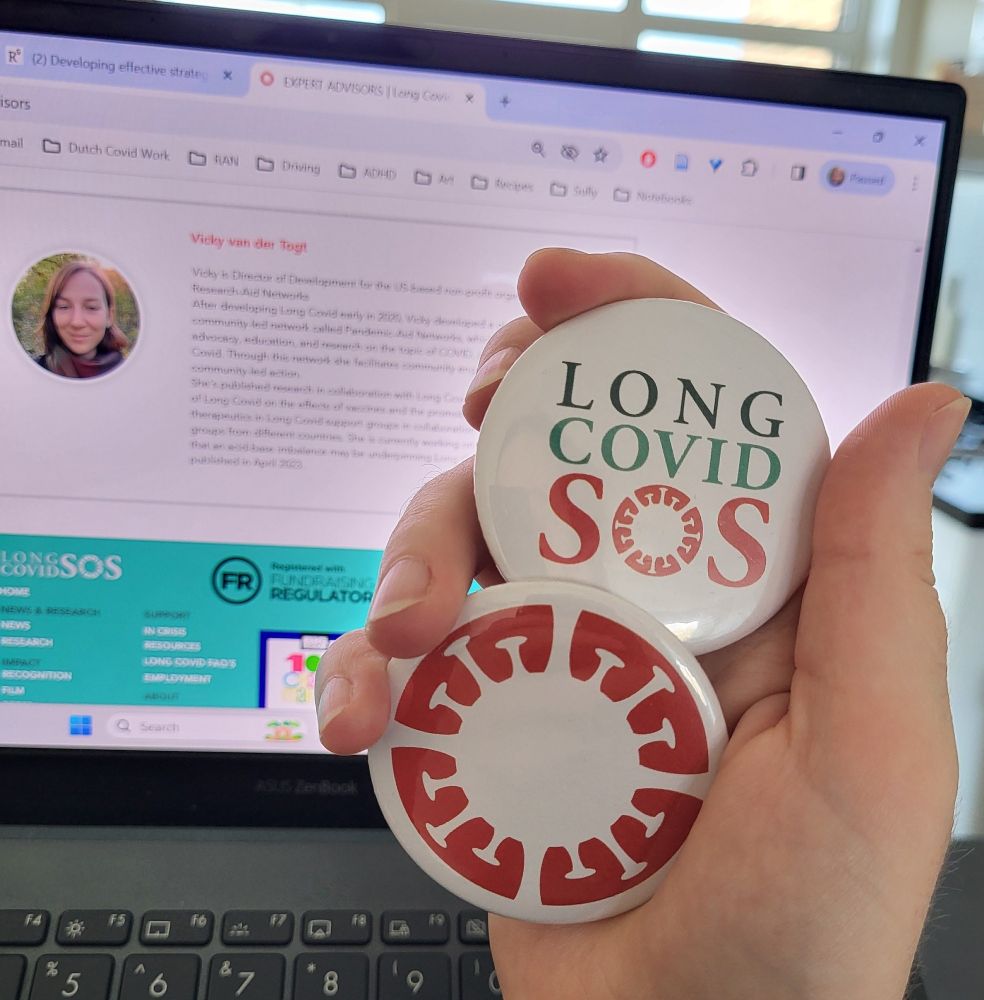 A photo of a hand holding 2 branded Long Covid SOS pins/buttons in front of a laptop with the long covid sos expert advisors page open showing the entry that lists my bio.