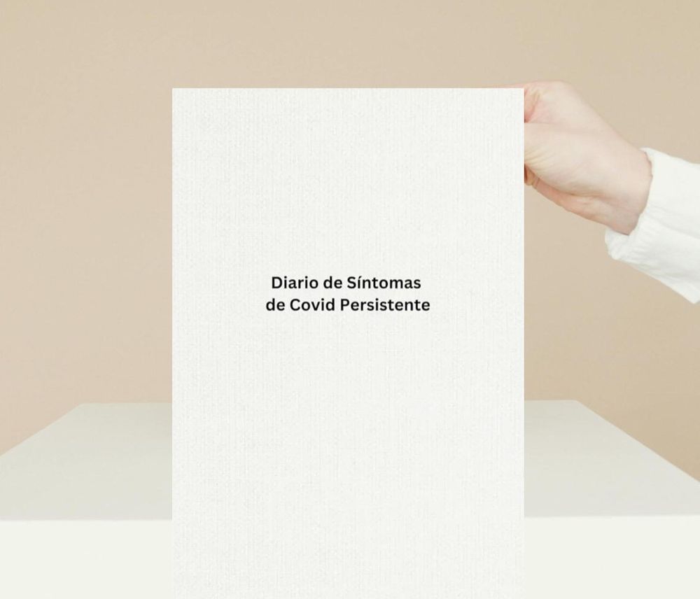 An image of a hand holding the Spanish version of the book, against a beige background. The title of the book reads 'Diario de Síntomas de Covid Persistente'