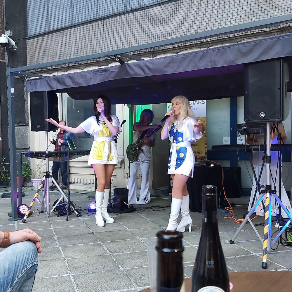 Photo of two ladies in cat minidresses singing outside.
