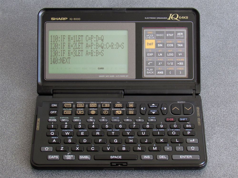 Photo showing an IQ-8000 electronic organiser editing a BASIC program in a large font. The BASIC program listing fills the screen (30x4 characters) instead of the usual 12x4 region.