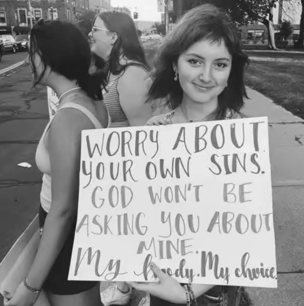A woman is holding a hand-lettered sign which reads:

WORRY ABOUT YOUR OWN SINS.
GOD WON'T BE ASKING YOU ABOUT MINE.
My body. My choice.