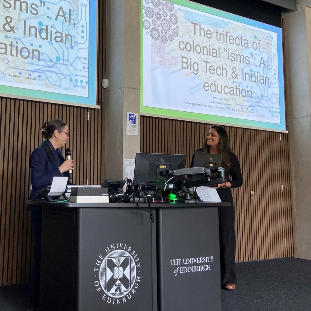 Professor Shannon Vallor introducing Meenakshi Mani at the CTMF PhD Showcase. Meenakshi's title slide is up on the projector screens and reads: The trifecta of colonial "isms": AI, Big Tech & Indian education