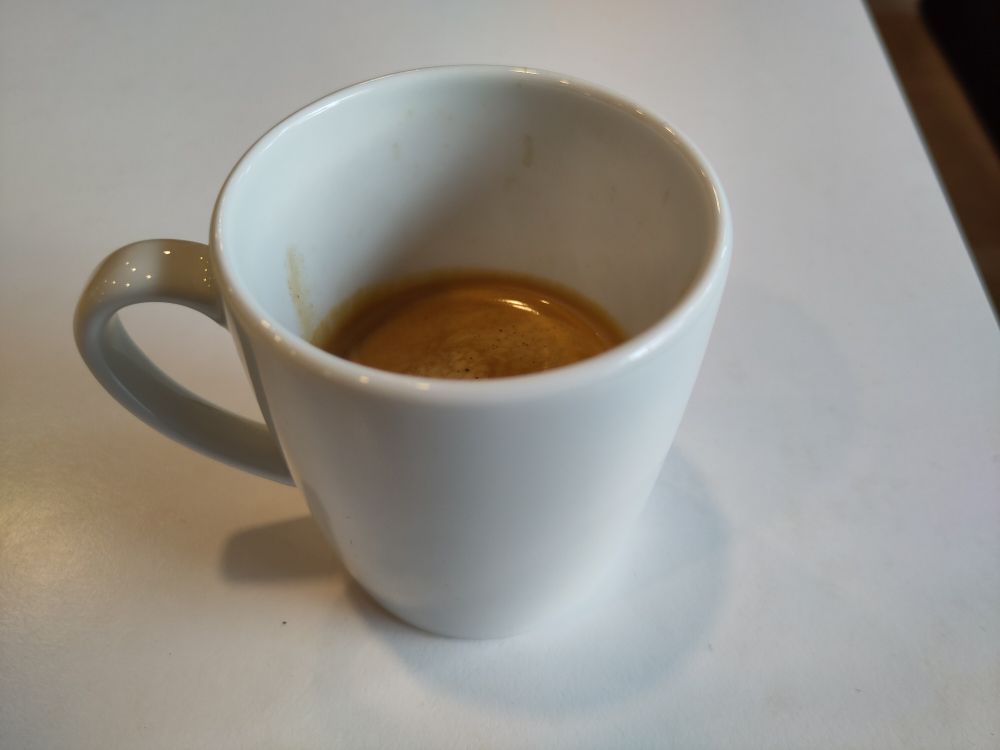 kleine Espresso in weißer Tasse auf weißem Tisch 