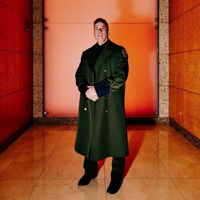 US Border Patrol Chief Greg Bovino at CNN's’s bureau in Chicago on Tuesday. In a long coat photographed against a marble interior with a red hue. He looks like a Nazi.