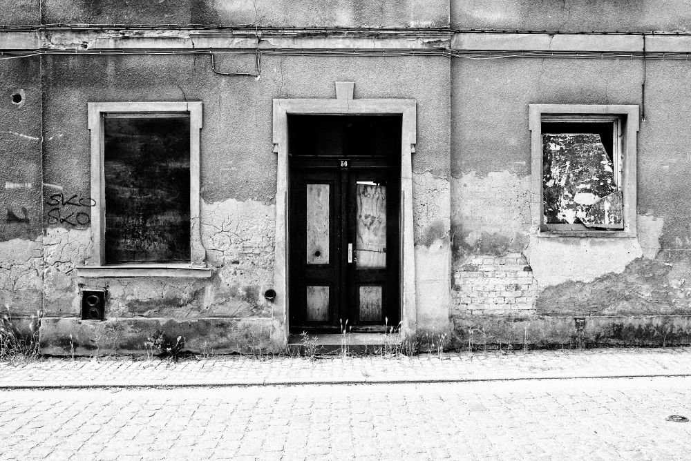 Abandoned house, front side with broken windows and main door.