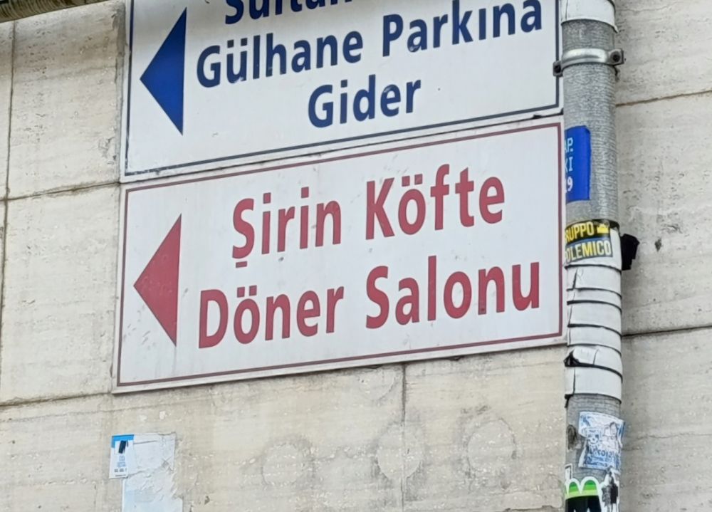 The sign says 'Şirin köfte'. Şirin is a name, but it's also what the Smurfs are called in Turkey