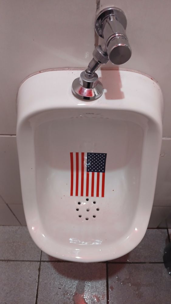 Foto e um mictório com a bandeira dos EUA estampada servindo de mira ^^