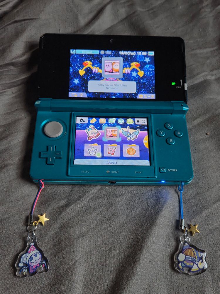 The two charms dangling from the bottom corners of my 3DS. The home screen theme is based on Marx's boss battle sprites.