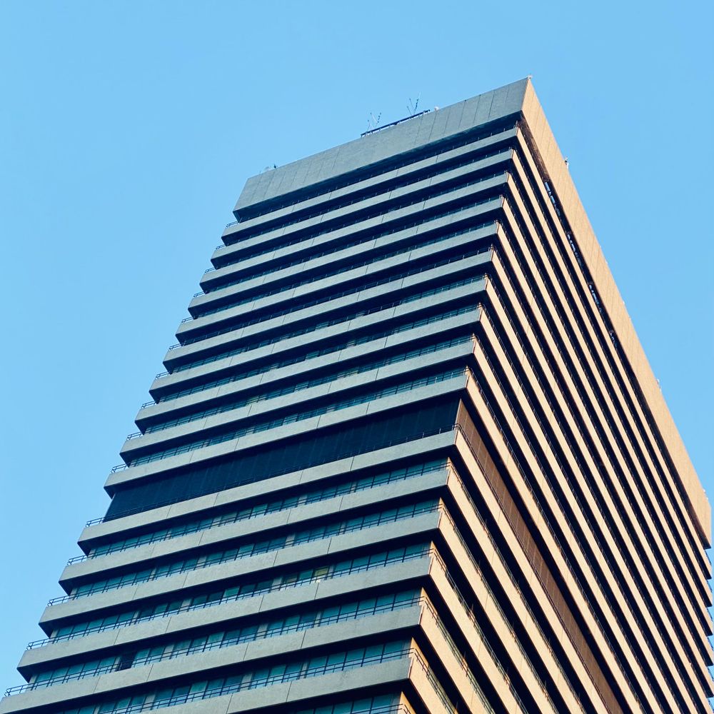 View up towards a brutalist tower, its many floors highly contrasting in the evening sunlight. The building is part of Guy‘s Hospital.