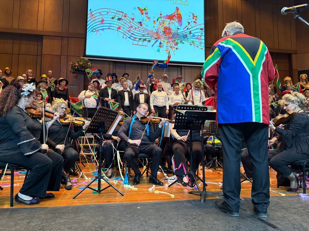 A picture from the concert mentioned in this post. The conductor is wearing a top in the style of the South African flag, the orchestra members are in various hats, glasses and other paraphernalia, and are covered in streamers, and the choir have all manner of weird and wonderful accessories, including a huge number of South African flags.