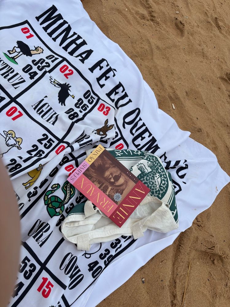 foto estética da canga do tema de jogo do bicho, com minha ecobag igualmente estética e o livro “paixão simples” da annie ernaux