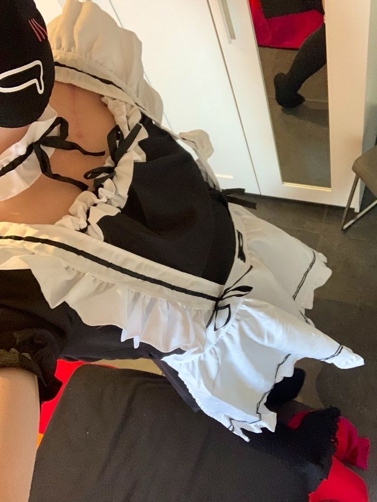 Femboy wearing a black and white maid outfit while wearing a facemask and thigh highs.