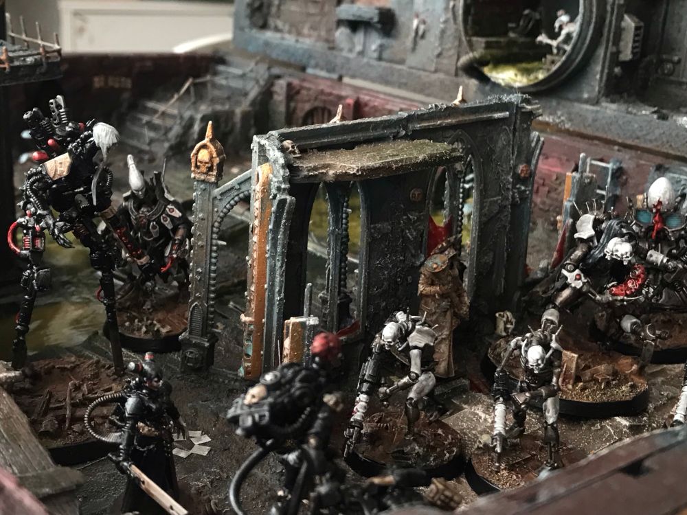 Necron miniatures kitbashed to be skinnier and scarier fighting three tall cyborg ladies clad in black in a ruined church in a sewer swamp