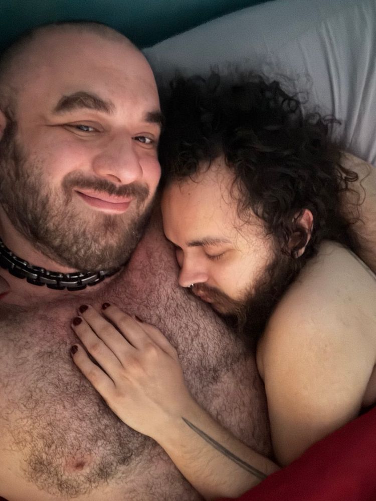 My head resting on my Giant's big strong chest. My hand can also be seen on his chest. My eyes are closed. He is looking at the camera and smiling. My hair is a mess. Nothing but love. ❤️