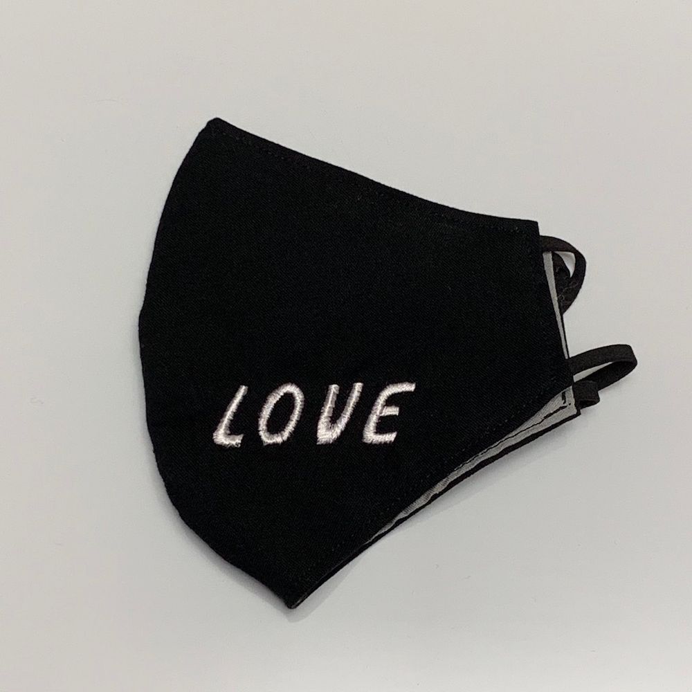 A black KN95 respirator with the words "LOVE" written on the front. 