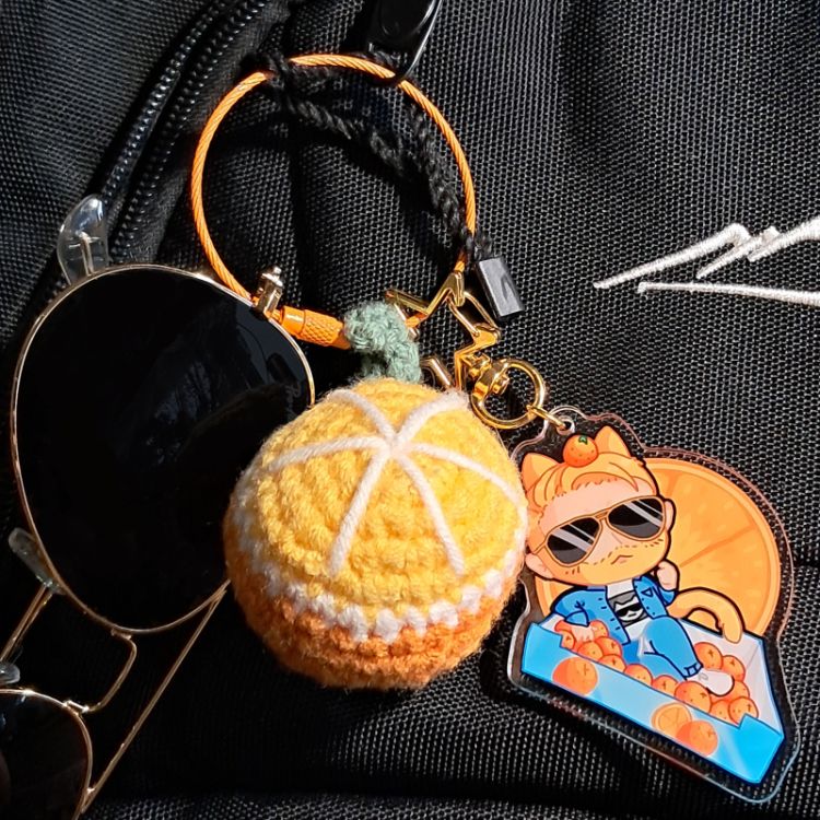chibi style acrylic keychain/charm of pro wrestler orange cassidy on a black back with other trinkets