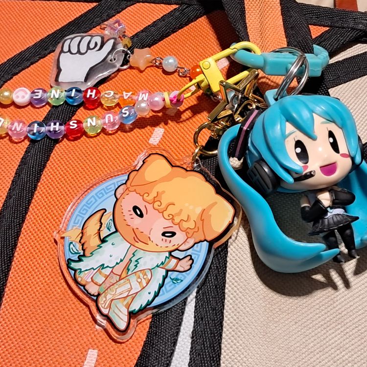 chibi style acrylic keychain/charm of pro wrestler on an orange bag with other trinkets