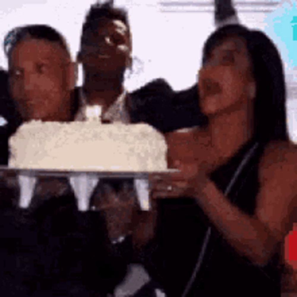 a group of people are holding a cake and blowing out candles on it .