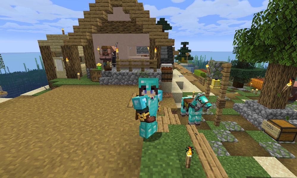 Minecraft screenshot: MandaLin's character wearing diamond armor, standing in a small village on an island. Villagers & a horse with diamond armor are in the background. 