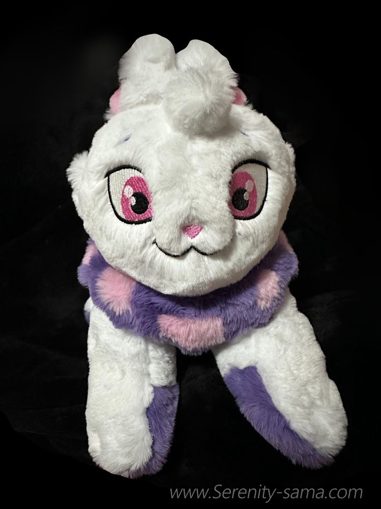 A fluffy plush toy of a Cybunny from the website Neopets. It is a white rabbit with large pink eyes, purple paw pads, and a fluffy purple dewlap around the neck with light pink spots.