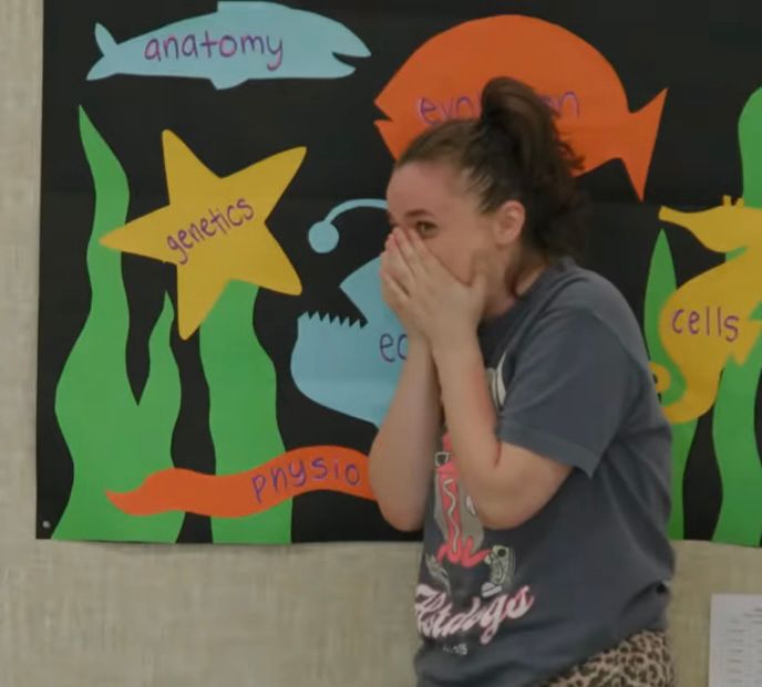Angela covering her face in shock and embarrassment after ratting out her teammate