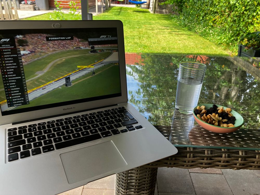 Mijn laptop op de tuintafel, met de F1 in beeld.
Ernaast een glas drinken en een schaaltje nootjes.
Met uitzicht op het grasveld 