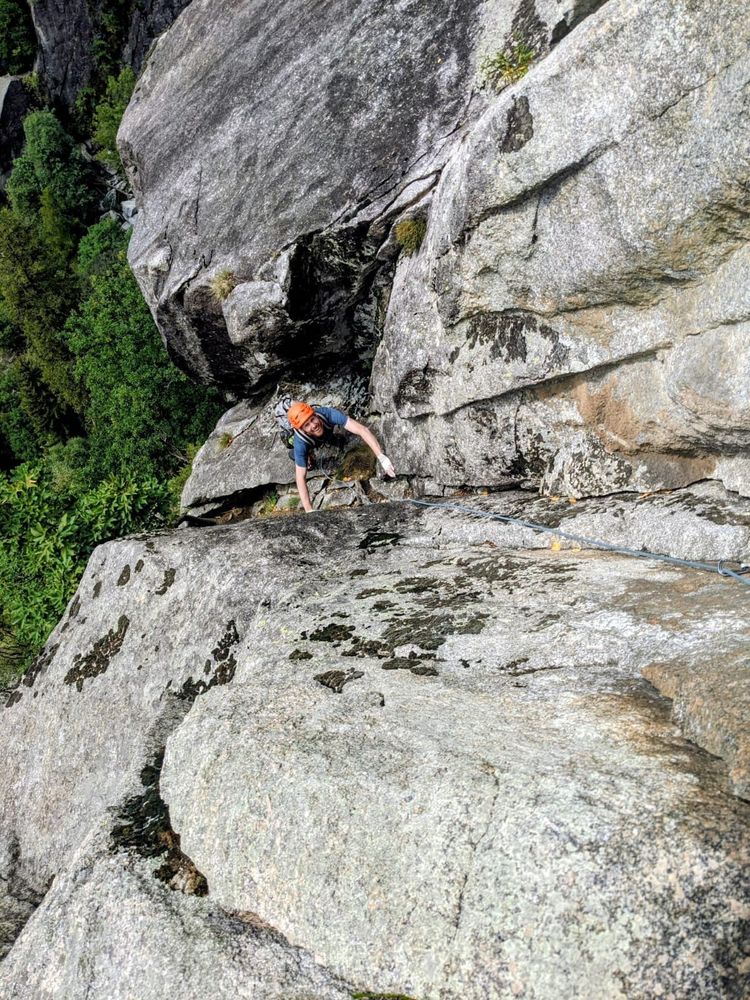 A climber smiling at the camera from a ledge.