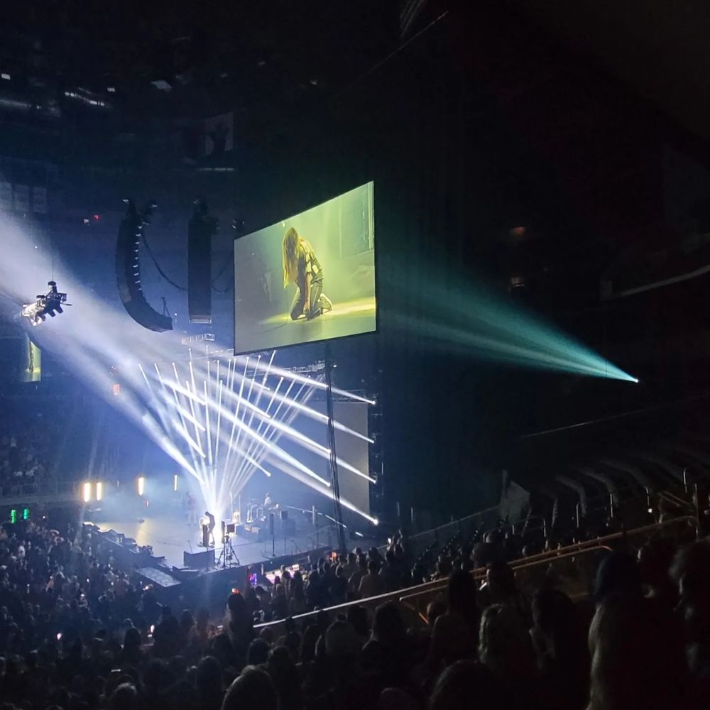 Strobelights and a screen in a dark arena, Alanis Morissette singing on her knees