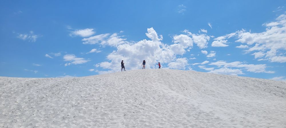 My husband and two kids on top of a dune in White Sands National Park during a heat wave