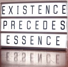 Illuminated cinema-style sign that reads:
EXISTENCE
PRECEDES
ESSENCE