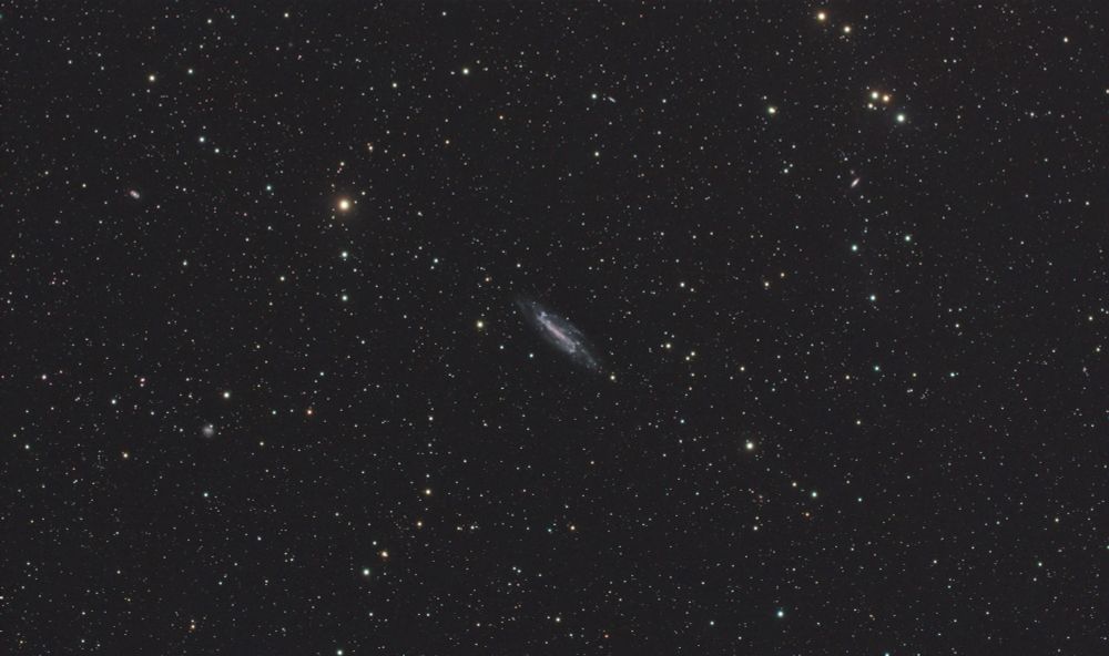 Galaxie spirale barrée assez petite au centre d'un ciel étoilé