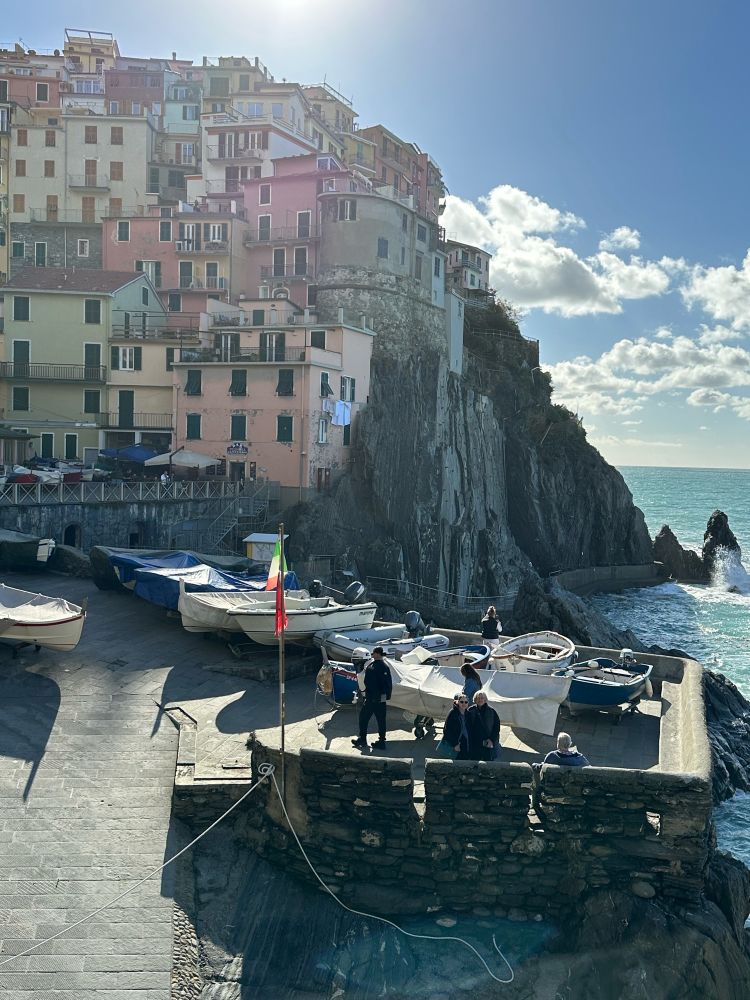 Colorful pastel hillside buildings in background , boats on ocean in foreground 