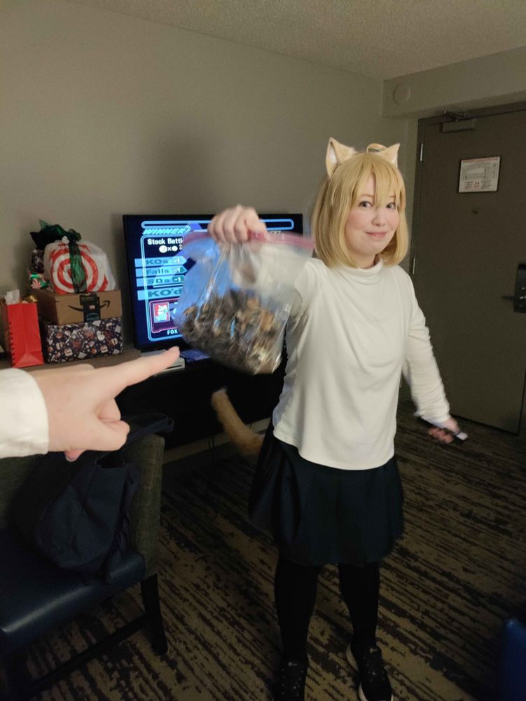 Neco arc holding up a bag with a smug face