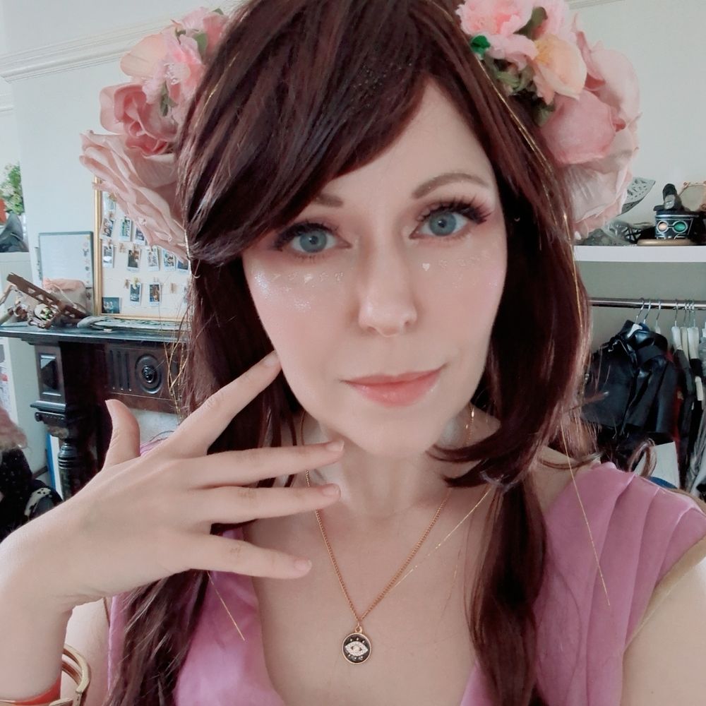 theStarlightFairy cosplaying as Circe. Their interpretation involves a reddish brown wig with gold tinsel, a large pink flower crown, gold makeup and a pink/purple dress with gold details