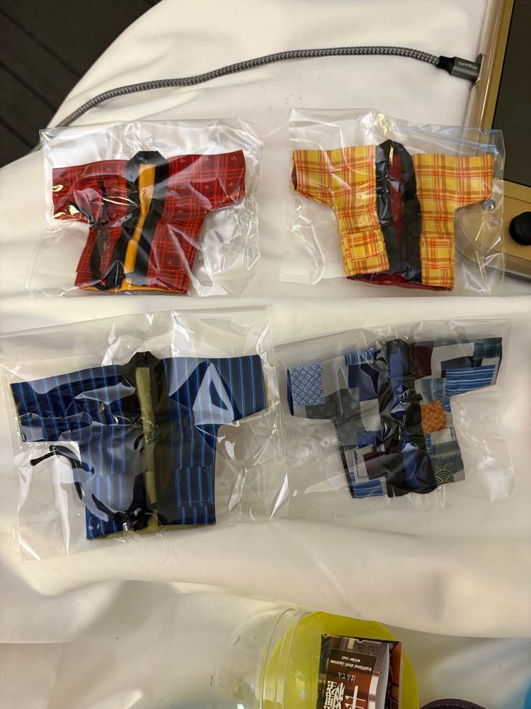 Mini doll-sized hanten jackets from the gatcha: red plaid, orange plaid, blue stripes, and blue patchwork. 