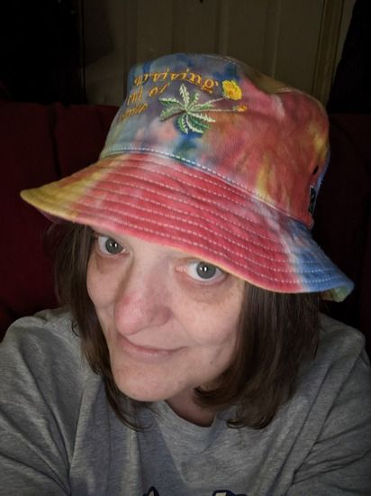 selfie in a tie dye bucket hat that says 'surviving out of spite'